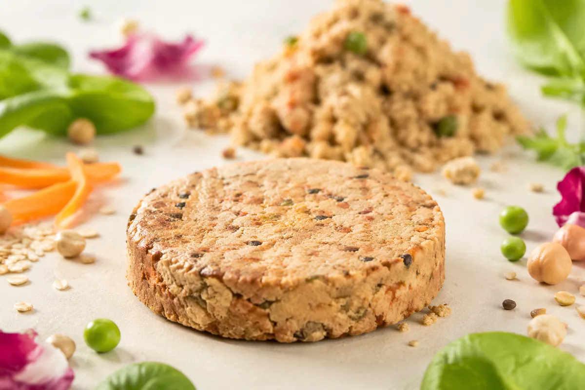 Formed plant-based patty in front of the loose plant-protein mince it was shaped from, the bind a methylcellulose replacement has to deliver